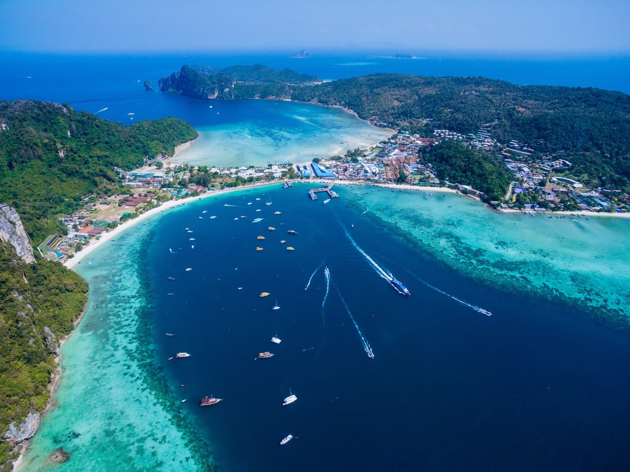 Aerial view of Tonsai Bay at Phi Phi Don Island, Thailand, showing clear blue turquoise water, coral reefs, and
